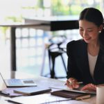 Female entrepreneur working with digital while sitting in modern workplace.