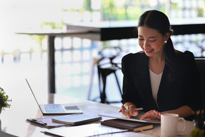 Female entrepreneur working with digital while sitting in modern workplace.