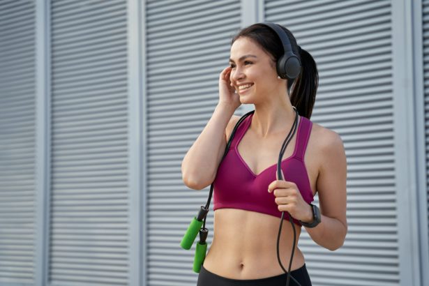 Smiling pretty ledy with jumping-rope using wireless headphones