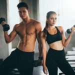 Sporty young couple with dumbbells in functional training fitness gym