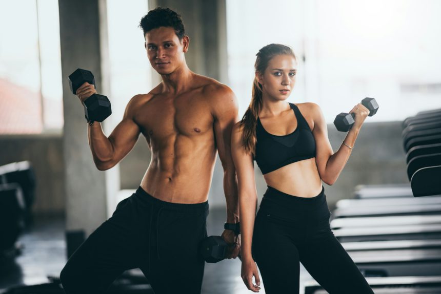 Sporty young couple with dumbbells in functional training fitness gym